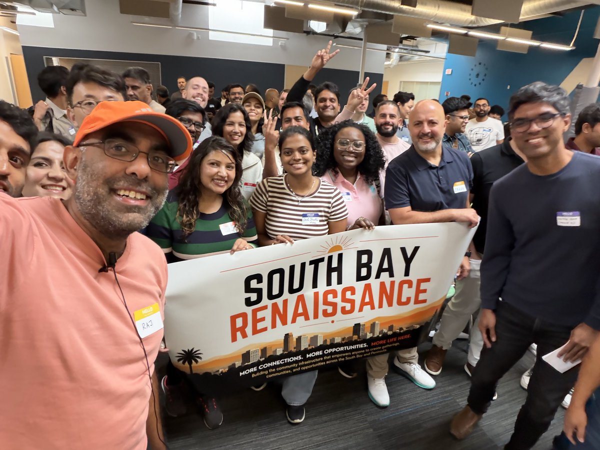 A packed room of South Bay Renaissance attendees smiling around the SBR banner at the first gathering